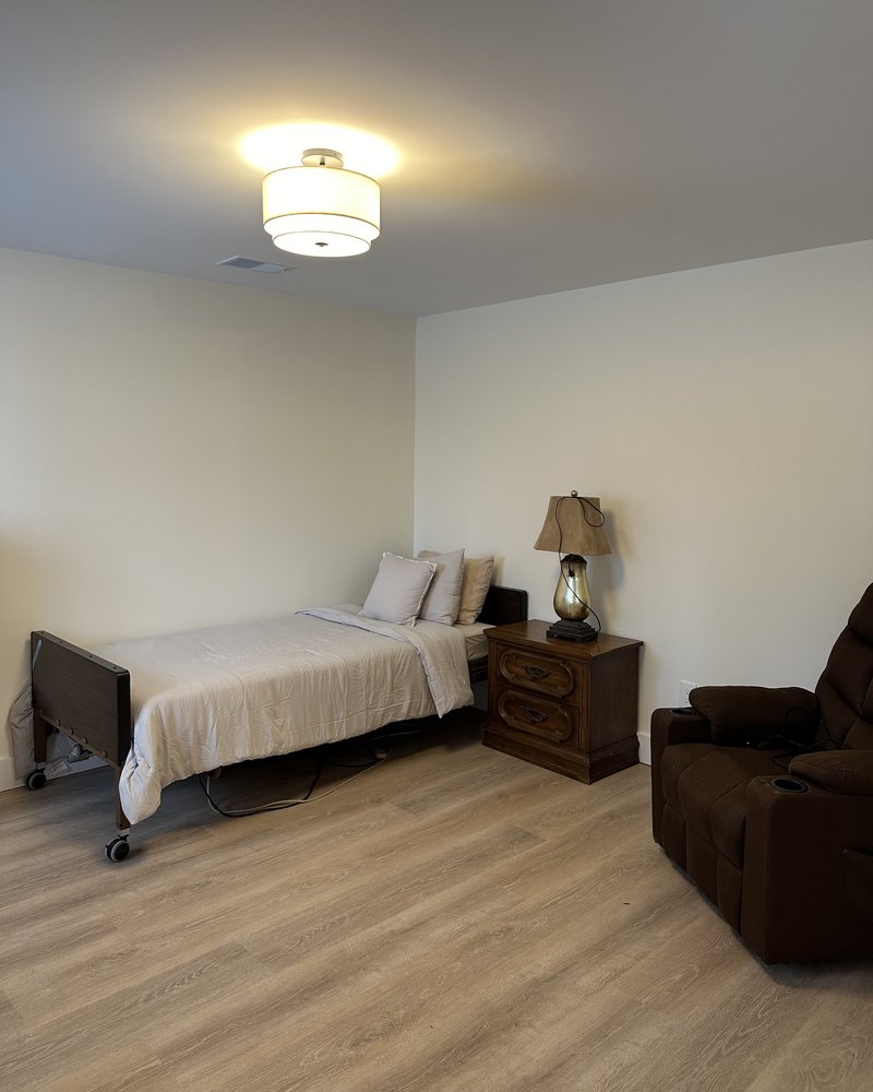 Resident bedroom with a hospital bed, nightstand lamp, and leather recliner