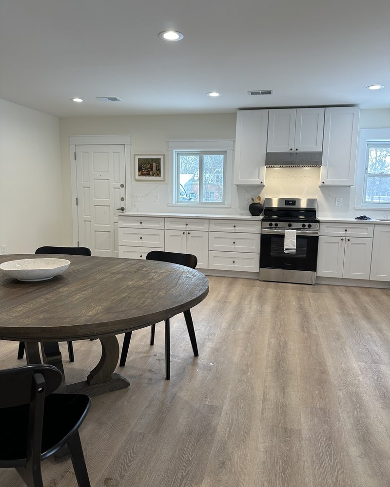 Open kitchen and dining area with white cabinets, a round table, and black chairs