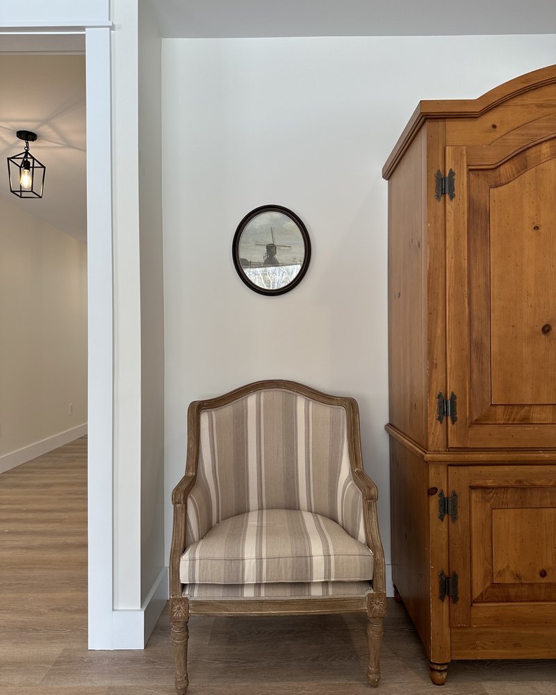 Cozy sitting nook with a striped armchair and wooden armoire